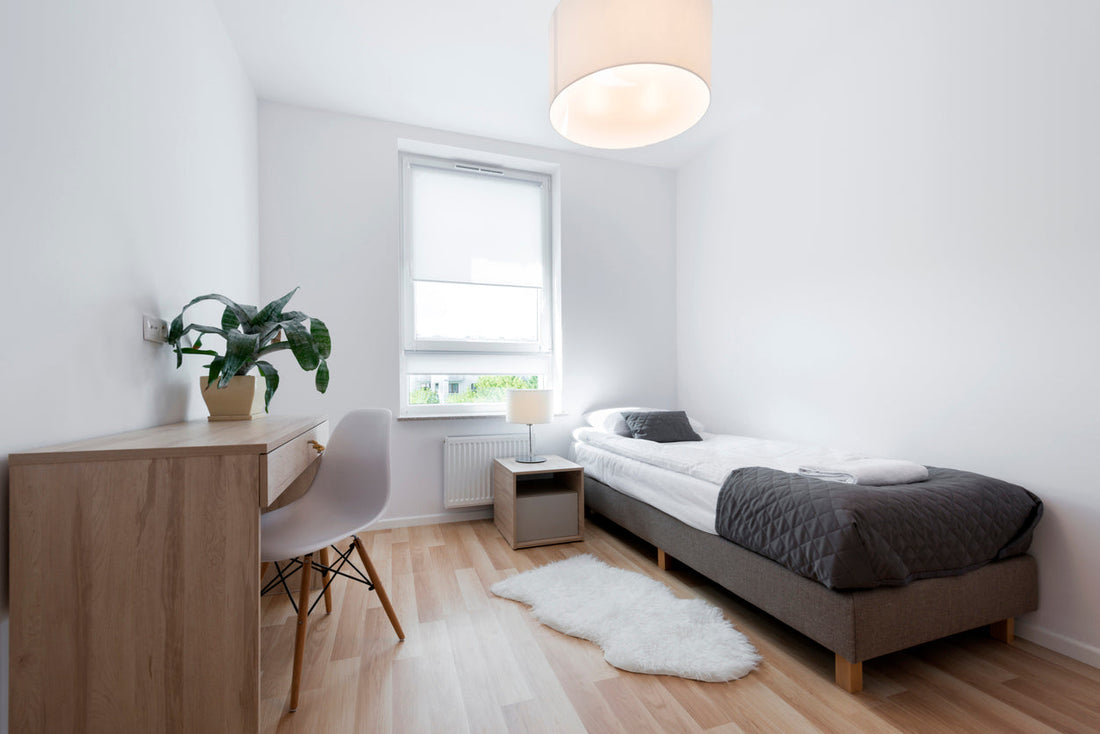 a student dorm room furnished with a bed and desk